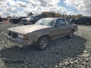 1987 Oldsmobile Cutlass z VIN 2G3GM11YXH2329442, wystawiony jako Copart lot #78805064 z przebiegiem 85 944 mil mil oraz Szkody całkowita. Historia ofert i sprzedaży dostępna na DreamBid. Obrazek 1.