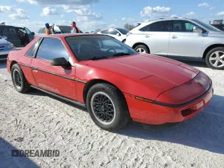 1988 Pontiac Fiero z VIN 1G2PE11R1JP219470, wystawiony jako Copart lot #77772864 z przebiegiem 94 011 mil mil oraz Szkody całkowita. Historia ofert i sprzedaży dostępna na DreamBid. Obrazek 4.