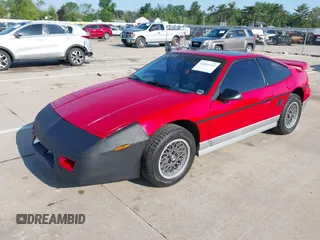 1986 Pontiac Fiero z VIN 1G2PG9791GP267415, wystawiony jako IAAI lot #42461769 z przebiegiem Nie podano mil oraz . Historia ofert i sprzedaży dostępna na DreamBid. Obrazek 2.