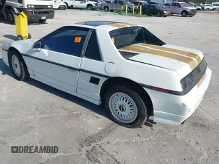 1986 Pontiac Fiero z VIN 1G2PF3797GP269850, wystawiony jako IAAI lot #40722755 z przebiegiem 129 077 mil mil oraz . Historia ofert i sprzedaży dostępna na DreamBid. Obrazek 3.