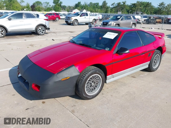 1986 Pontiac Fiero z VIN 1G2PG9791GP267415, wystawiony jako IAAI lot #42461769 z przebiegiem Nie podano mil oraz . Historia ofert i sprzedaży dostępna na DreamBid. Obrazek 2.
