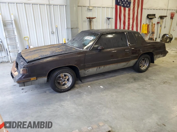 1987 Oldsmobile Cutlass z VIN 1G3GR1195HP307304, wystawiony jako Copart lot #83901444 z przebiegiem 4856 mil mil oraz Nie do naprawy. Historia ofert i sprzedaży dostępna na DreamBid. Obrazek 1.
