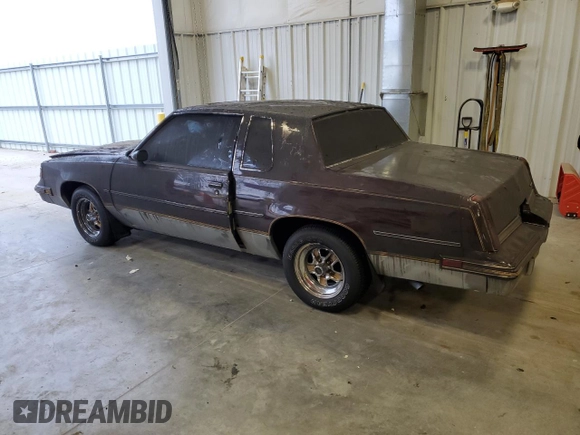 1987 Oldsmobile Cutlass z VIN 1G3GR1195HP307304, wystawiony jako Copart lot #83901444 z przebiegiem 4856 mil mil oraz Nie do naprawy. Historia ofert i sprzedaży dostępna na DreamBid. Obrazek 2.