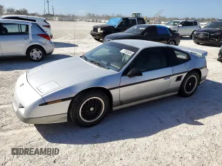 1986 Pontiac Fiero z VIN 1G2PG9799GP261135, wystawiony jako Copart lot #77305934 z przebiegiem 53 837 mil mil oraz Szkody całkowita. Historia ofert i sprzedaży dostępna na DreamBid. Obrazek 1.