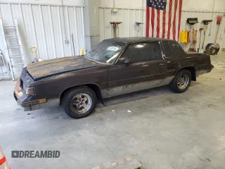1987 Oldsmobile Cutlass z VIN 1G3GR1195HP307304, wystawiony jako Copart lot #83901444 z przebiegiem 4856 mil mil oraz Nie do naprawy. Historia ofert i sprzedaży dostępna na DreamBid. Obrazek 1.